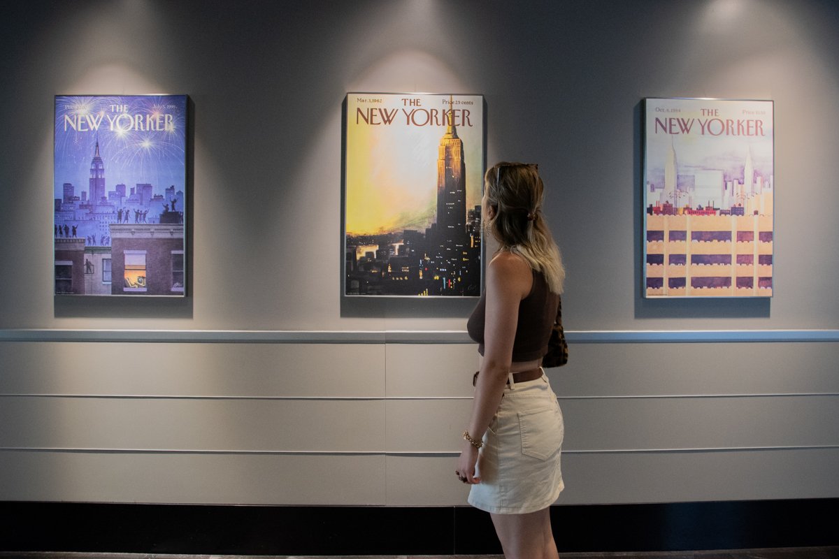 Femme qui regarde les affiches de the New Yorker dans le hall