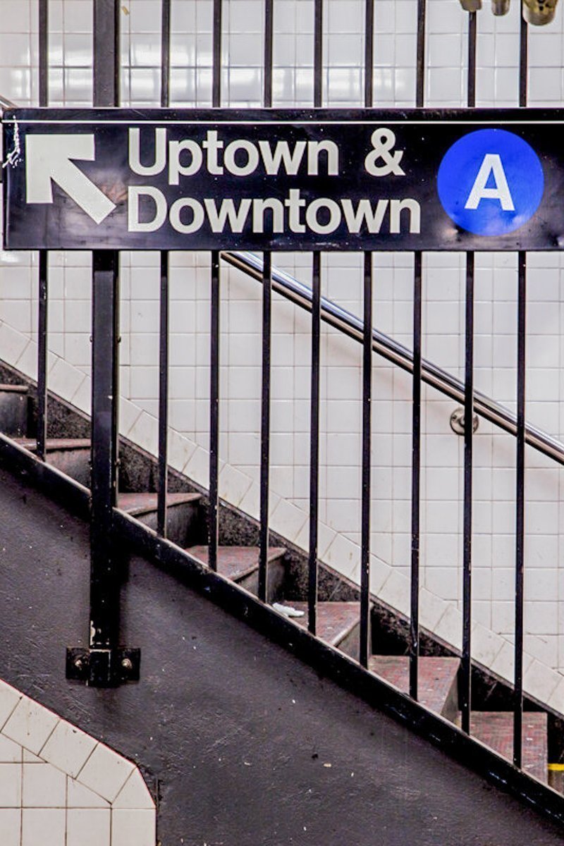 New York City Subway inside and underground with steps and directional sign for Uptown Downtown A train.