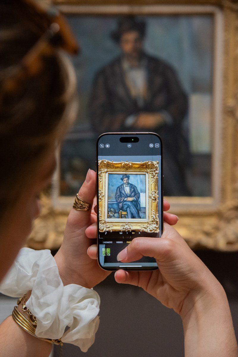 Femme qui prend en photo une peinture de Paul Cézanne