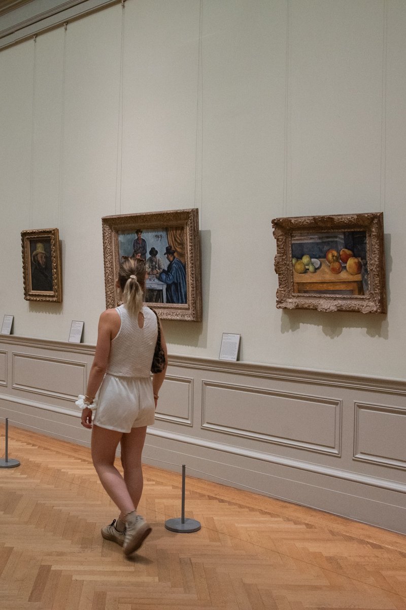 Femme qui marche dans une salle avec des tableaux