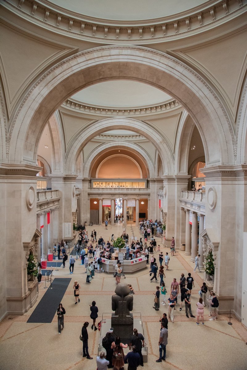 Grande salle haute avec des arcades et des visiteurs qui se promènent