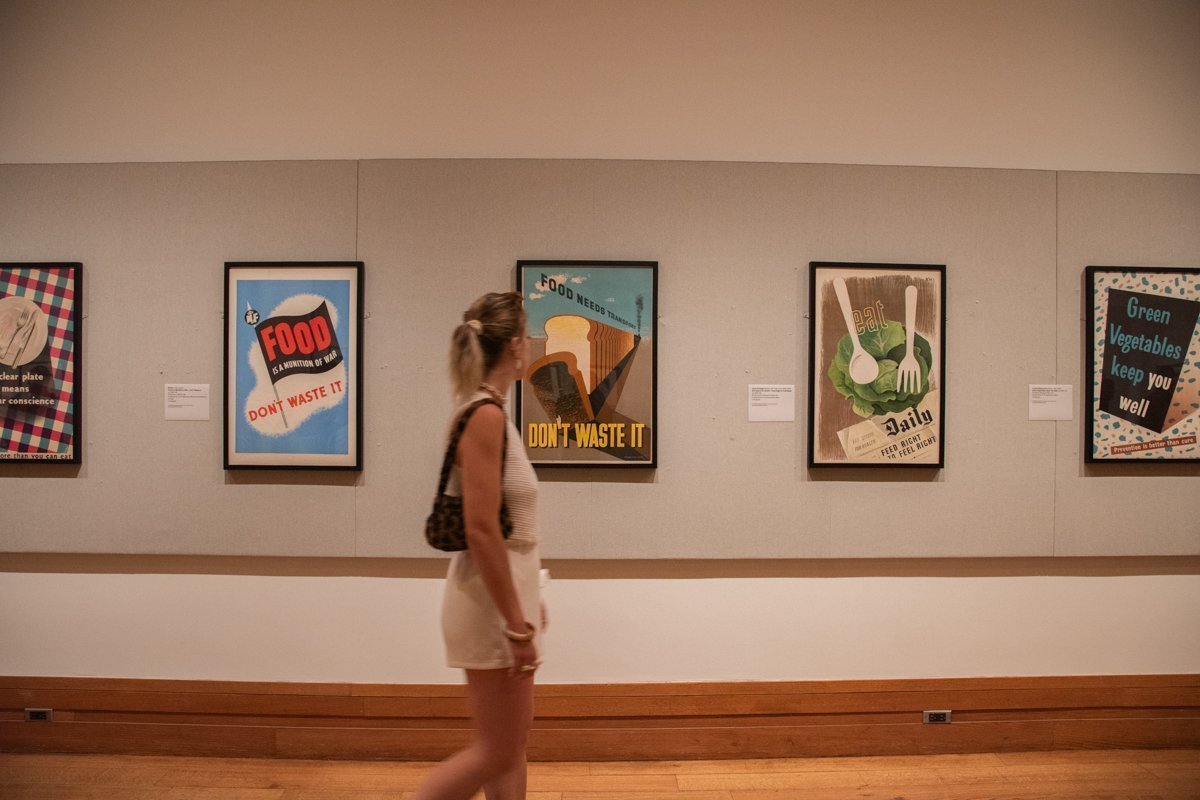 Femme qui marche dans une salle en regardant d'anciennes affiches