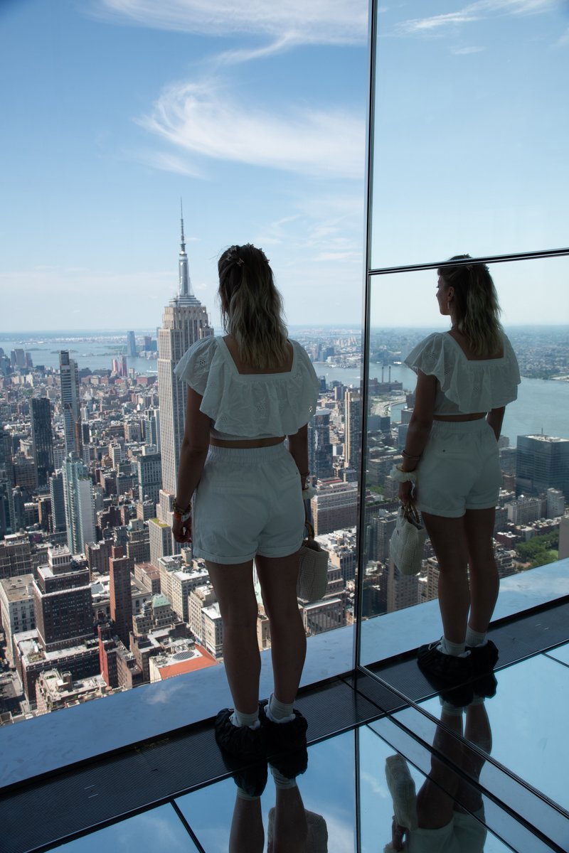Femme qui regarde l'Empire State Building à travers la vitre